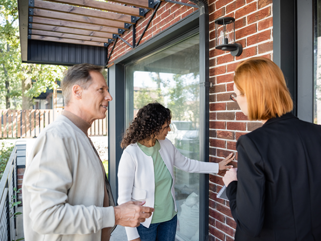 Couple viewing the exterior of a home with real estate agent