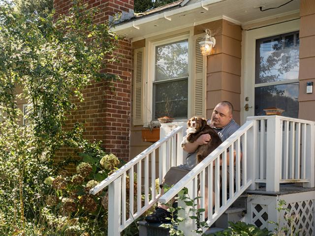 Person and dog sit on front porch