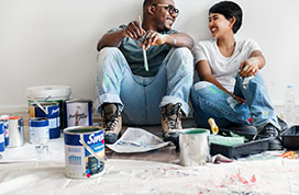 Man and woman laughing while painting their house
