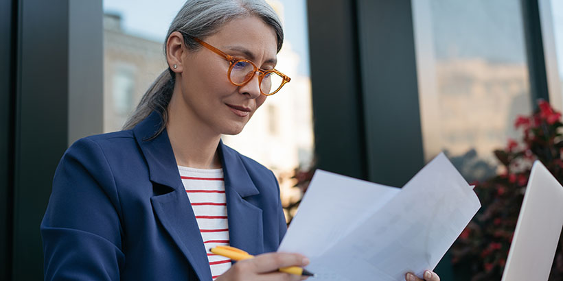 Gray-haired woman analyzing important reports.
