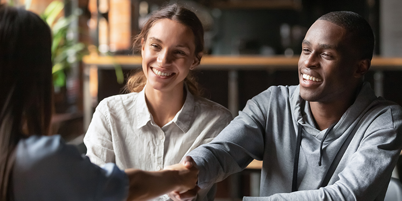 New homebuyers shaking hands with housing professional