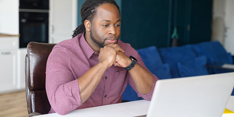 Man with hands on chin contemplates computer screen