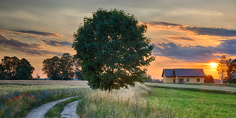 Sun setting behind a house on a rural road