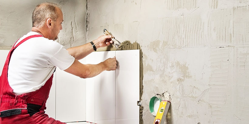Gray-haired man tiles his bathroom.