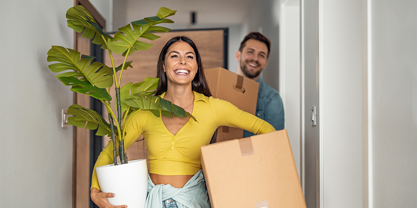 Couple carrying moving boxes and a plant