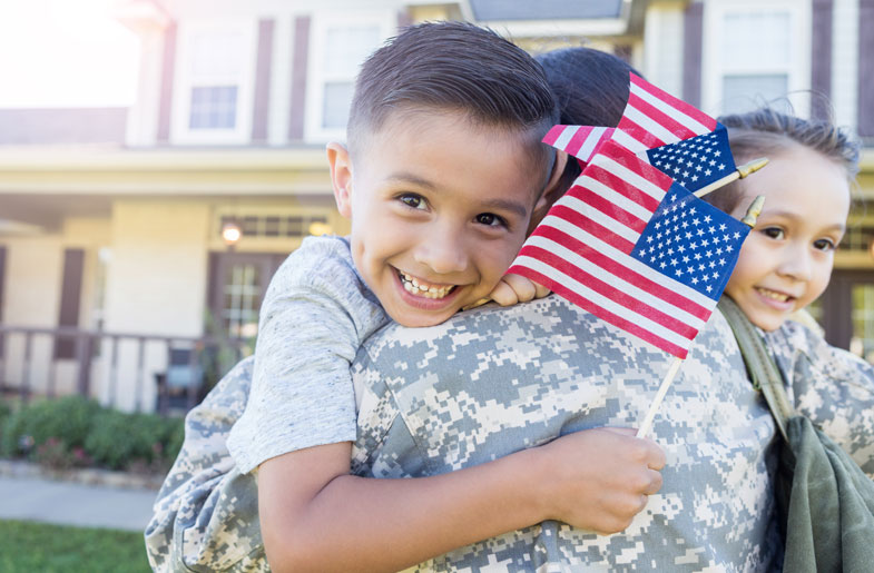 Image of soldier hugging small children holding American flags