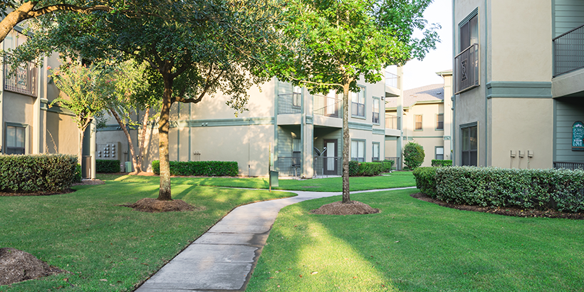 Tree-lined walkway leading into a rental community