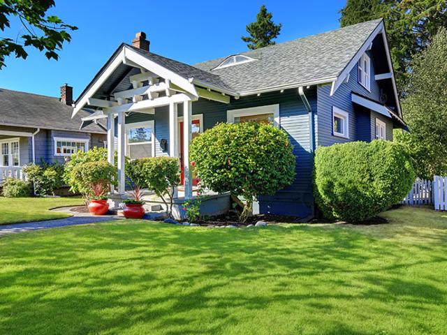 Blue Craftsman house with green lawn