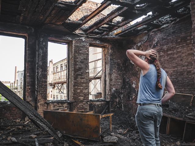 Woman looking at burnt house