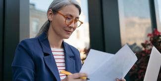 Gray-haired woman analyzing important reports.