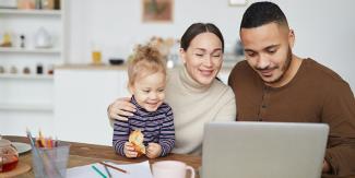 Father, mother and child all smiling at a laptop screen