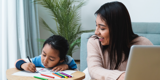 Adult watches child coloring in the living room