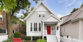 Small, move-in ready gray house with a bright red door and outdoor furniture