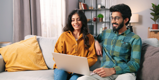 Couple on couch looking at a laptop