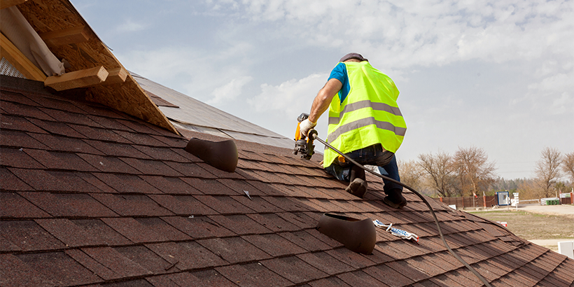 Person installing shingles on roof