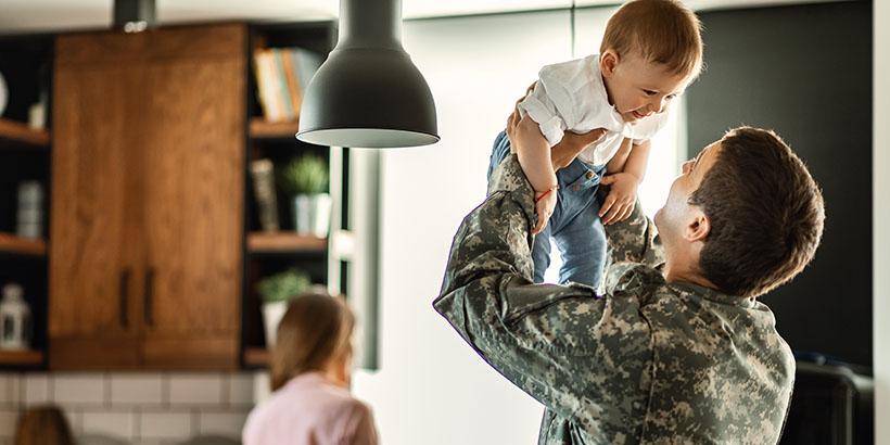 Serviceman holding his smiling child in the air