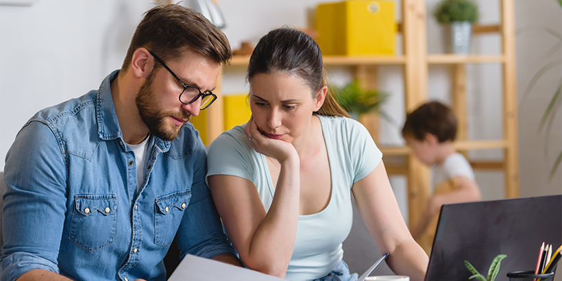 Couple reviewing paperwork while child plays in the background