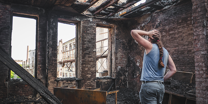 Woman looking at burnt house
