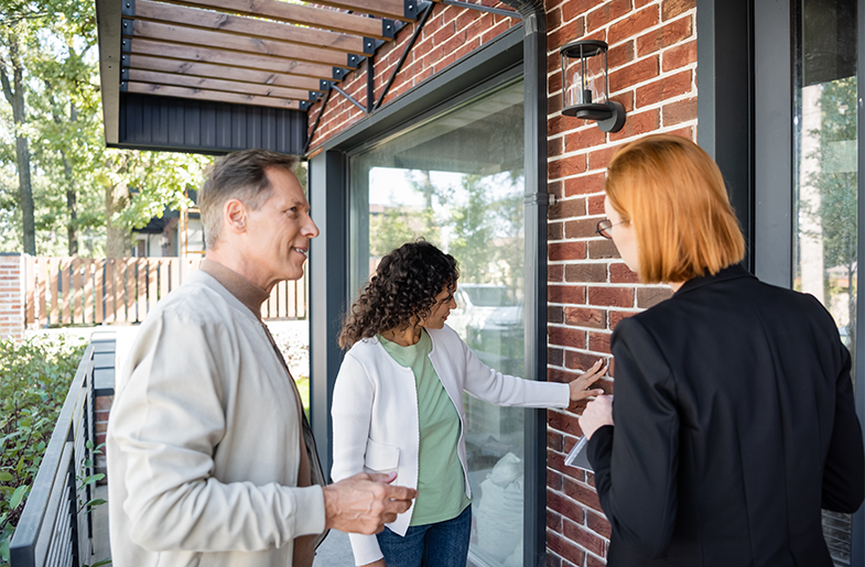 Couple viewing the exterior of a home with real estate agent
