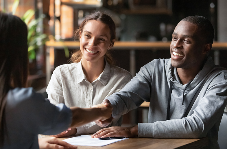 New homebuyers shaking hands with housing professional