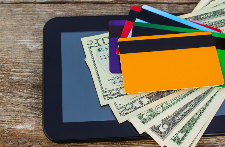 Colorful credit cards on a stack of twenty-dollar bills with a tablet background, symbolizing financial health
