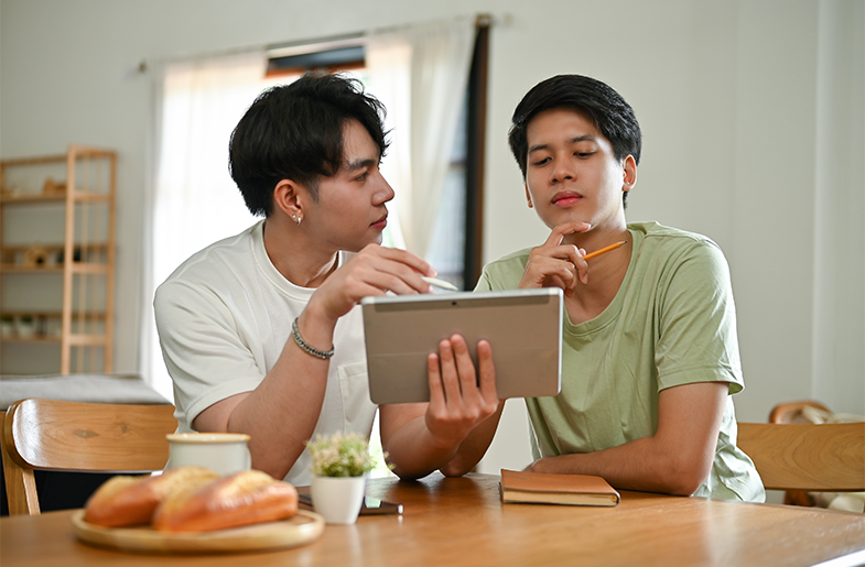 Couple sitting at kitchen table with a tablet and notepad