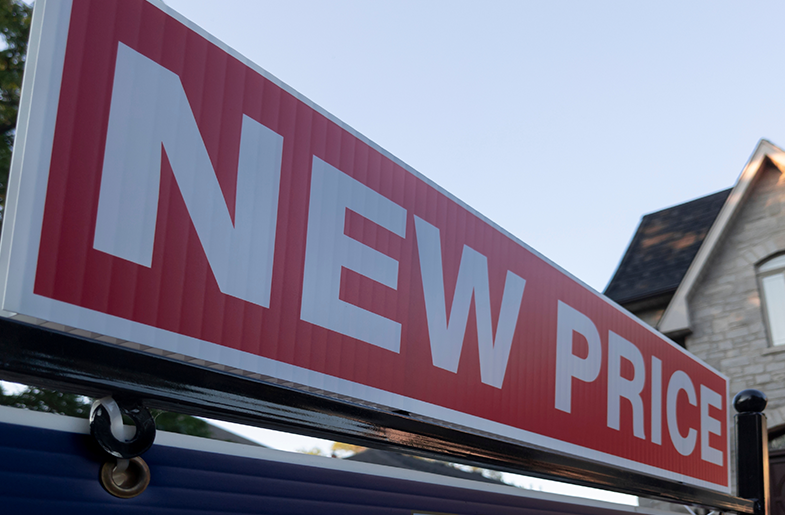 Home with a "For Sale" sign indicating a new price