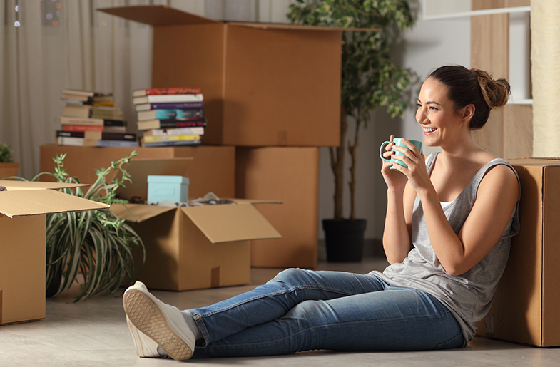 Woman sitting on floor with coffee surrounded by boxes
