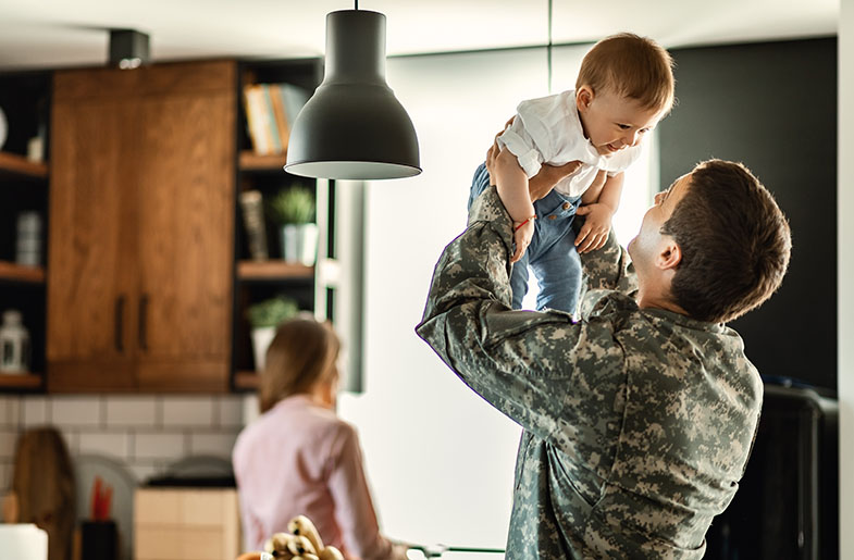 Serviceman holding his smiling child in the air