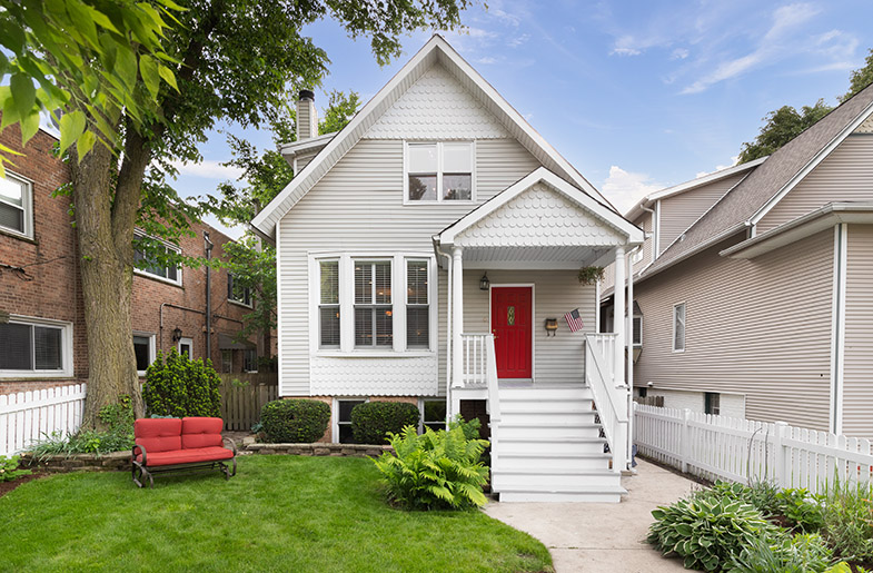 Small, move-in ready gray house with a bright red door and outdoor furniture