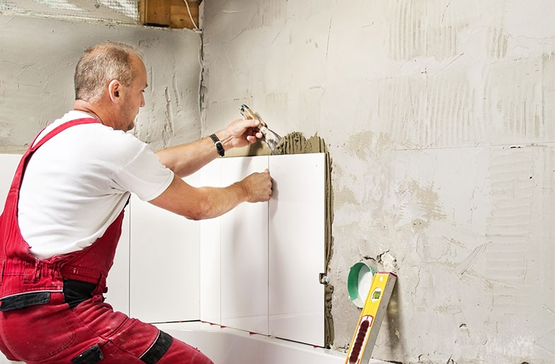 Gray-haired man tiles his bathroom