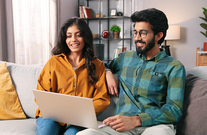 Couple researching together on the living room couch with laptop.