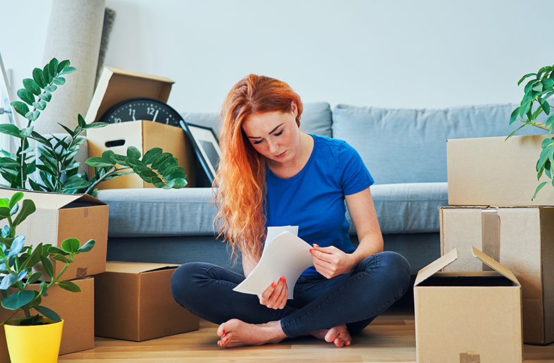 Young woman reviewing lease information surrounded by packing boxes.