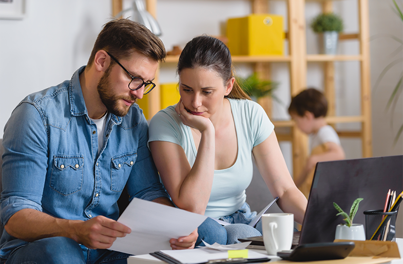 Couple reviewing paperwork while child plays in the background