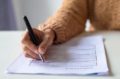 person filling out a form with a pen