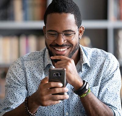 Close-up of a man smiling, looking at the cell phone